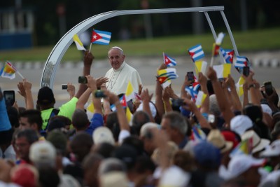 HAVANA, CUBA - SEPTEMBER 20: People wave Cuban and Papal flags as Pope Francis passes by as he arrives to perform Mass on September 20, 2015 in Revolution Square in Havana, Cuba. Pope Francis is on the first full day of his three day visit to Cuba where he will meet President Raul Castro and hold Mass in Revolution Square before travelling to Holguin, Santiago de Cuba and El Cobre then onwards to the United States.  (Photo by Carl Court/Getty Images)