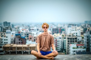 young man meditating with cityscape