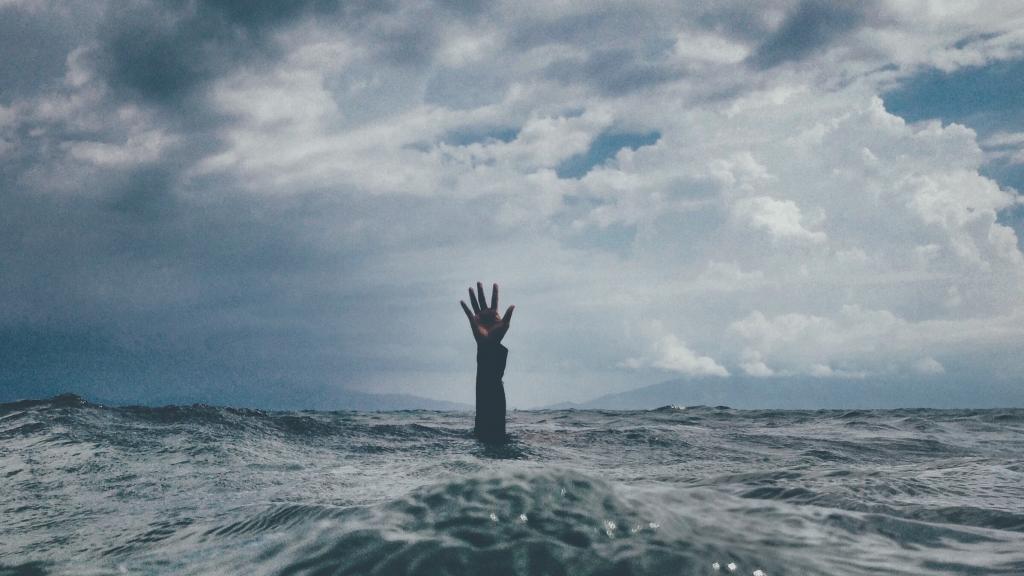 a human hand reaching up out of a large body of water