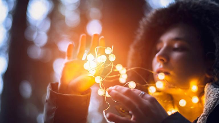 Woman looking at and touching golden fairy lights