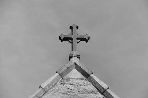 a cross on the roof of a church in black and white