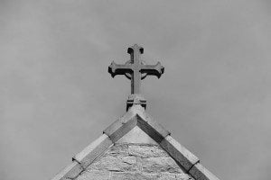 a cross on the roof of a church in black and white