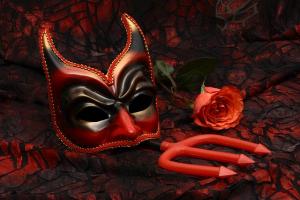 a devil mask with a pitchfork on a red tablecloth