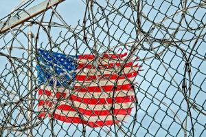 the United States flag behind prison barbed wire