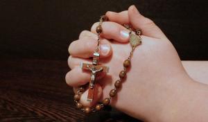 hands clutching a Rosary