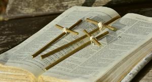 a Bible with three wooden crosses