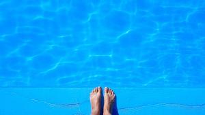 a pair of feet soaking in a blue swimming pool