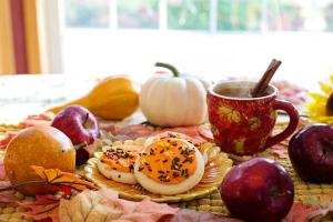A table of Autumn leaves and fruit with a cup of cider