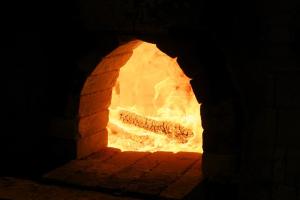 the opening to a brick oven, with a bright orange burning log inside