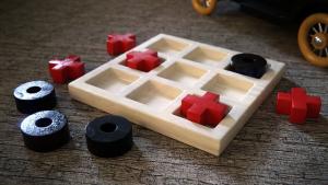 a wooden tic tac toe board with red X's in it