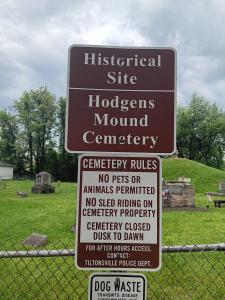 A sign reading "Historical site, Hodgens Mound Cemetery, Cemetery Rules: No pets or animals permitted, no sled riding on cemetery property, cemetery closed dusk to dawn." 