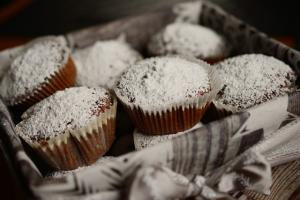 muffins topped with powdered sugar, in a tray with a tea towel 