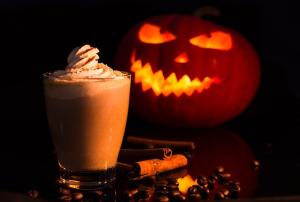 a cup of hot chocolate with fancy whipped cream in front of a Jack O'Lantern 