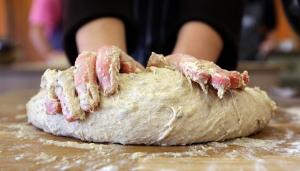 hands kneading bread dough on a board