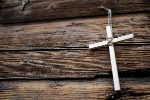 a small cross hanging on a wooden wall