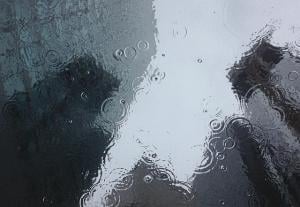 rain drops in a puddle, reflecting blurry buildings