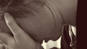 A child or young woman with her face covered by one hand, crying. Dobson encouraged parents to hurt their children until they cried. 