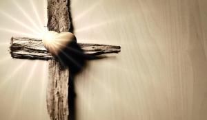 a sepia photograph of a cross with a heart in the middle. The cross is rough wood, but the heart is smooth and seems to glow.