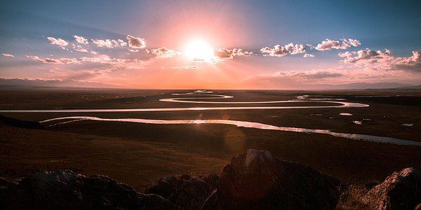 A prairie river winds across the plan at sunset.