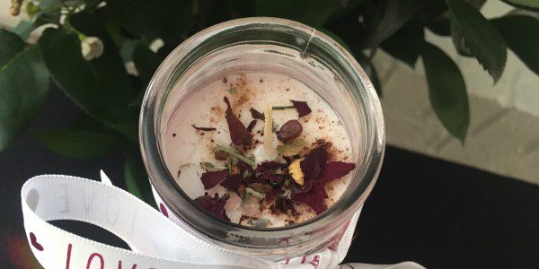 Top of decorated Love Candle sprinkles with a few herbs, stone chips and drops of Love-Drawing oils.