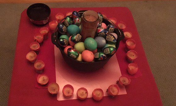 Cauldron of dyed hard-boiled eggs and cadbury chocolate eggs, with a Glass sanctuary candle in the middle to charge them, and our Fires of Aries candles in a ring around them, ready for lighting individually during the rites. ~ Heron Michelle