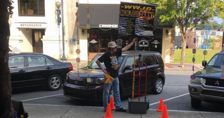 "EC Street Preacher" witnessing outside of The Sojourner with his "Who Would Jesus Damn?" sign, August 26, 2017. Photo Credit: Heron Michelle