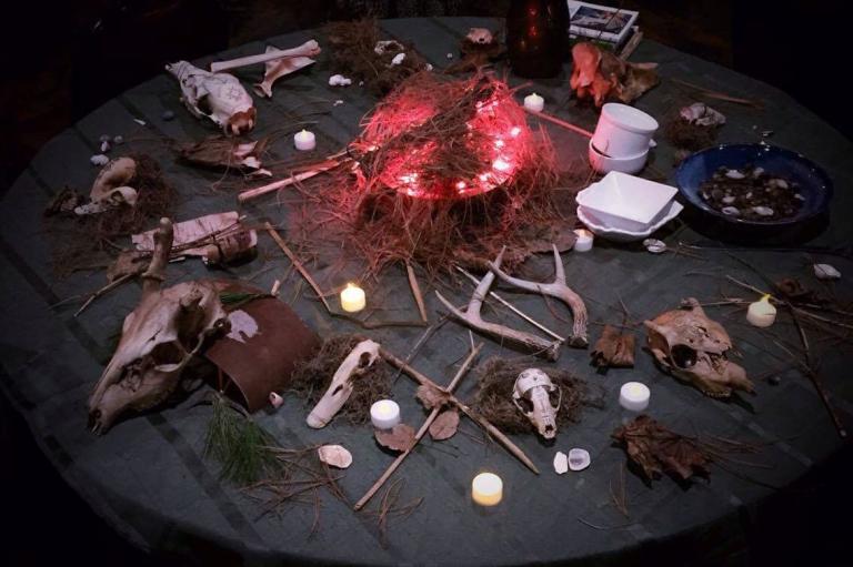 A table with skulls, bits of natural stuff and a glowing light in the center.