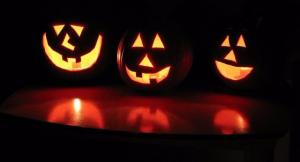 Three Jack-O-Lanterns glowing in the dark. 