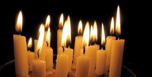 Many candles burning in a group with a dark background.