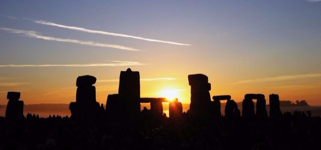 An image of Winter Solstice at Stonehenge with the sun just rising over the stones.