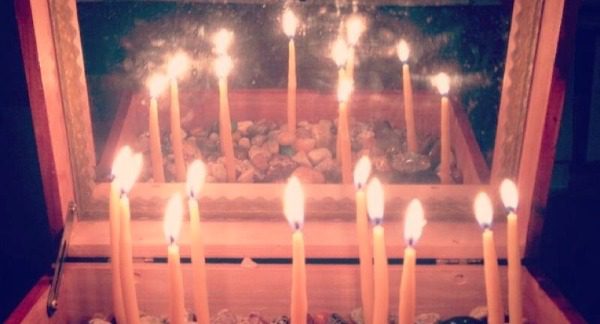 a box with candles lit within it reflecting in a mirror in the box lid to make a circle of candles.