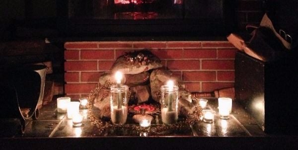 An altar of death and renewal created by Rev. Hill. It has a cave build of stones against a red brick backdrop with many candles lit. 