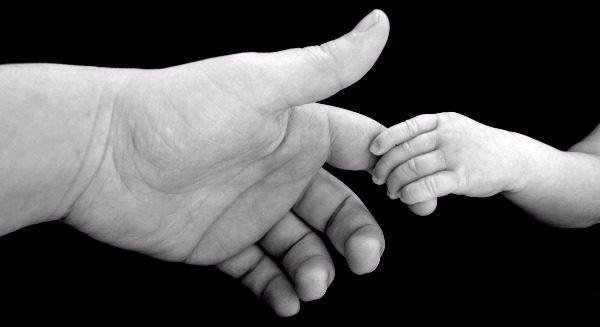 A parent holding the hand of a baby.