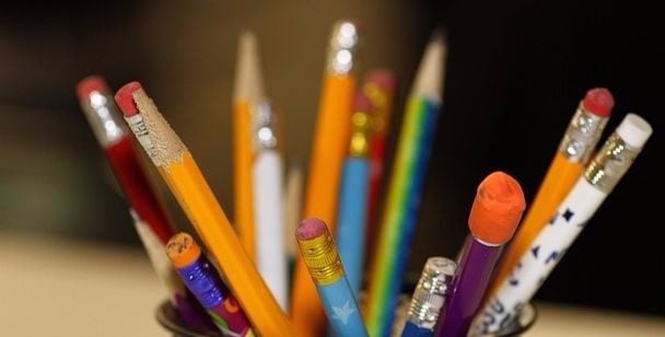 A selection of kids pencils swirling out of a mug. They show wear and eraser use. These are working pencils.