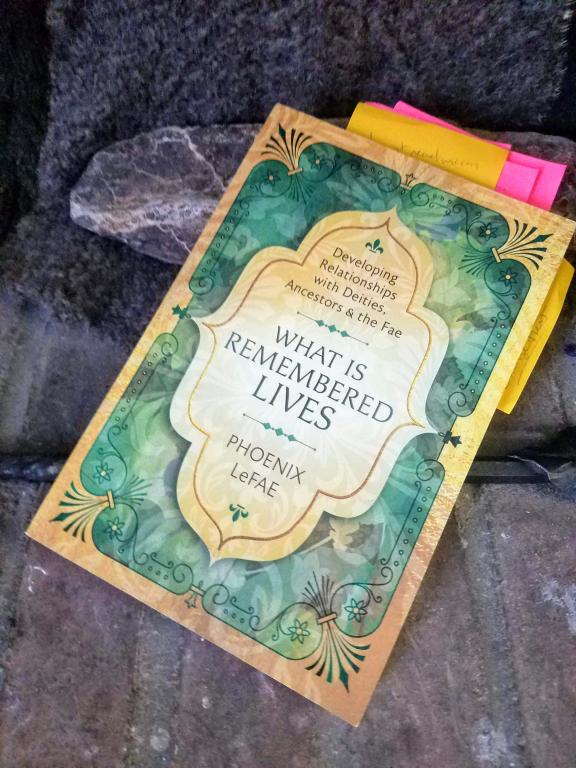 A copy of What is Remembered Lives with a number of sticky notes as bookmarks, sitting on a stone hearth. 