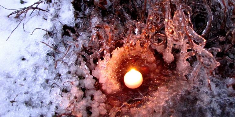 a small candle is burning in an ice covered hollow of a tree.