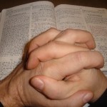 Hands praying over Bible