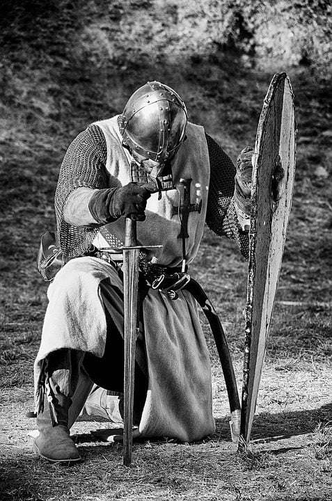 Picture of crusader with sword and shield, kneeling in prayer. 