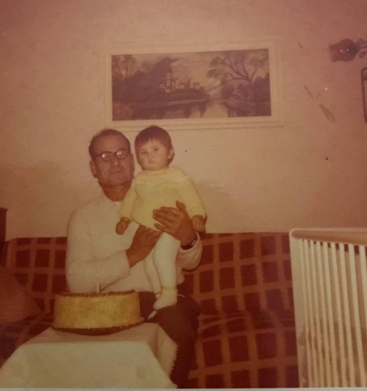 Old, sepia-toned photo of a man with glasses holding a little girl