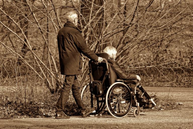 Man pushing woman in wheelchair