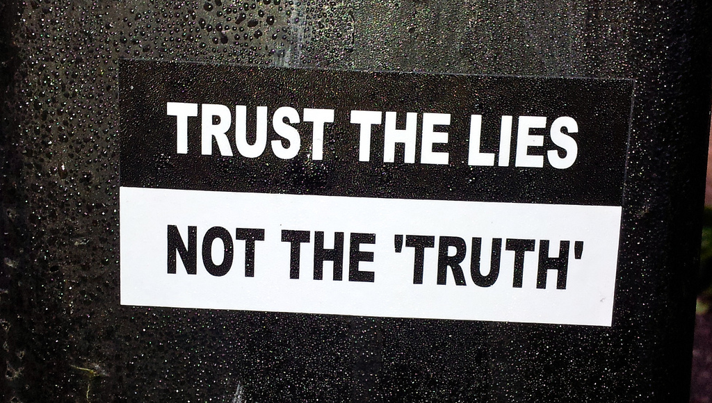 photo saying “trust the lies, not the ‘truth’” (Thomas Guest/Flickr)