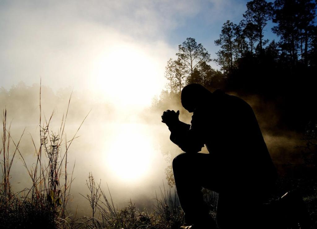 silhouette of man praying at waters edge at dawn