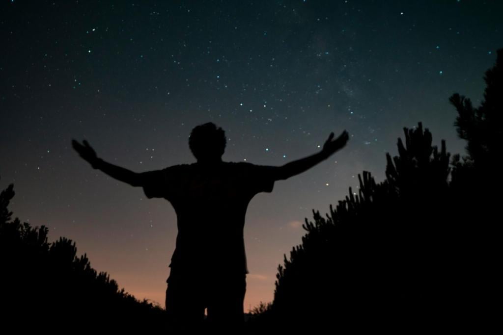 Man lifting hands beneath a night sky