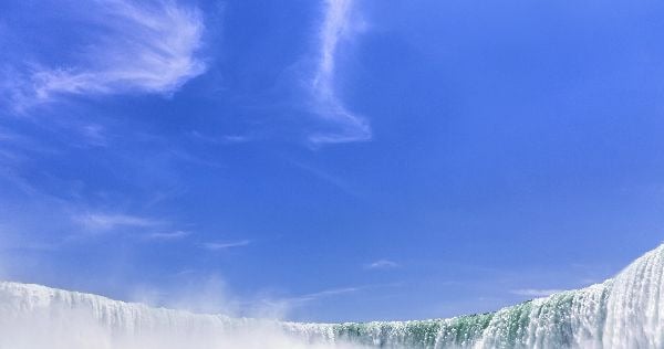 calm blue sky above raging waterfall