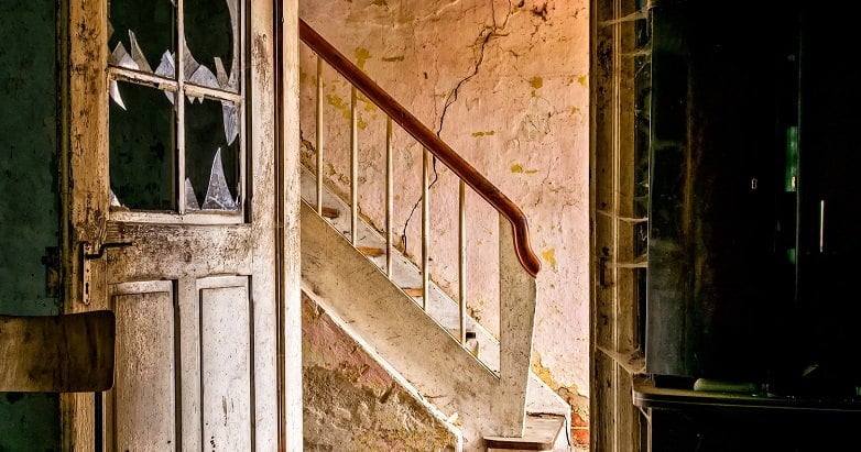 A color photograph of a staircase in a dilapidated house.