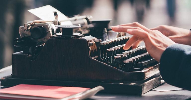 Photo of a person's hands typing on a manual typewriter.