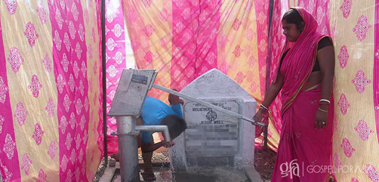 Gospel for Asia founded by Dr. K.P. Yohannan: A local woman pumps water for her daily use from the new well on the day it was dedicated. Her family is no longer threatened by waterborne illness that had been impacting her community.