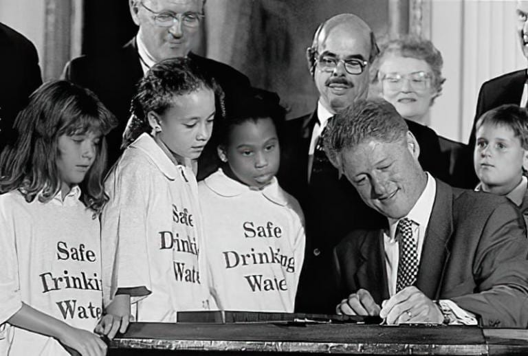 President Clinton signs the amendments to the Safe Drinking Water Act as children and others watch.