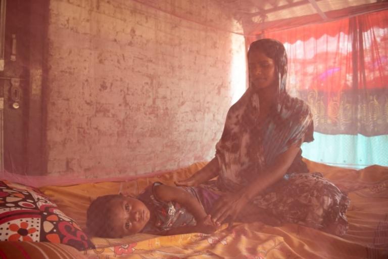 Mother and child resting under mosquito net