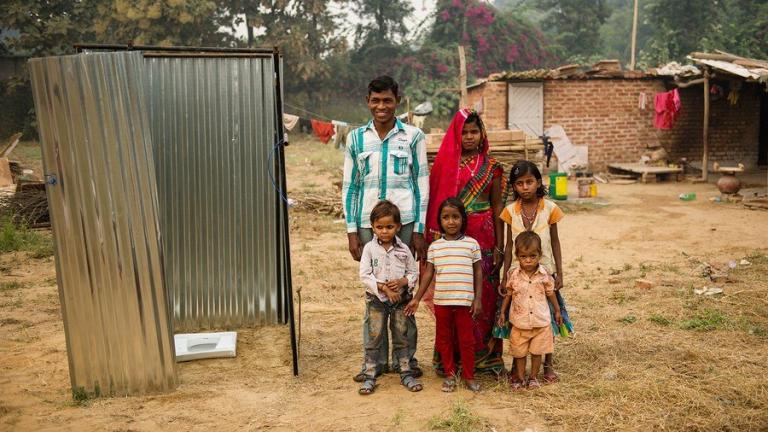 A family stands in front of a India toilet - a GFA-installed latrine or squatty potty.